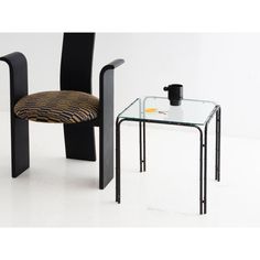 a glass table with a chair next to it on a white floor, and a zebra print cushion