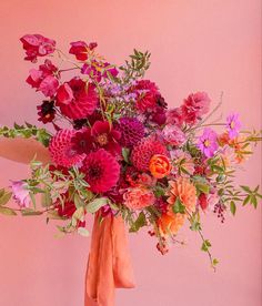 a vase filled with lots of colorful flowers on top of a pink table next to a wall