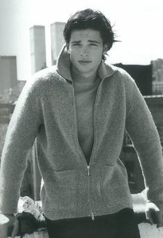 black and white photograph of a young man leaning against a railing with his hands on his hips