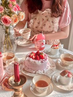 a woman sitting at a table in front of a cake with strawberries on it