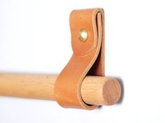 a close up of a wooden handle on a white wall with a brown leather strap