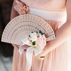 a woman in a pink dress holding a white flower and a fan with flowers on it