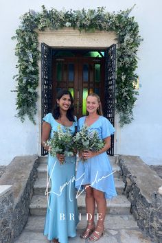 two women standing in front of a doorway holding bouquets of flowers and greenery