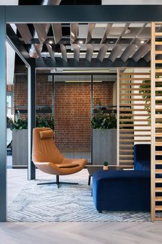 a living room with blue couches and wooden slatted walls, along with a planter on the wall