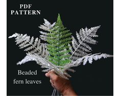 a person holding a fake fern leaf in their hand with the text, beaded fern leaves