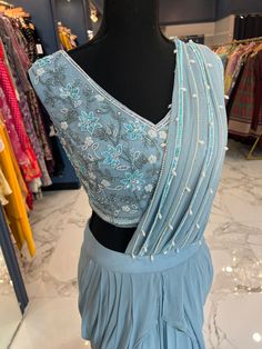 TO ORDER LARGER SIZES, PLEASE WHATSAPP +1 (945) 444-2194 Powder Blue Handwork Ready saree accentuated with pearl and bead work. Crafted with a "V" neckline and a flattering pearl and bead work on the saree pallu (ornamental end piece). paired with a trendy skirt style bottom and attached pleats. Slight variation in color is possible due to digital photography. Shipping will take 2 weeks,Please WHATSAPP +1 (945) 444-2194 for more info. Elegant Light Blue Choli For Festive Occasions, Elegant Light Blue Festive Choli, Semi-stitched Embellished Blue Saree, Semi-stitched Embellished Blue Blouse Piece, Blue Pre-draped Saree With Mirror Work For Party Wear, Blue Bollywood Embellished Pre-draped Saree, Embellished Sleeveless Formal Sets, Designer Floor-length Saree With Pearl Embroidery, Designer Floor-length Pre-draped Saree With Pearl Embroidery