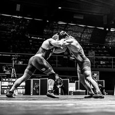 two men wrestling in an arena during a competition