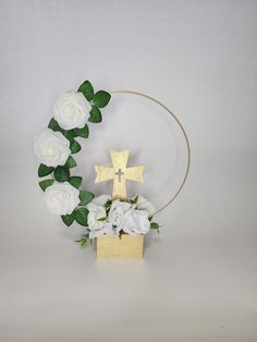 a cross and some white flowers on a table with a circular object in the background