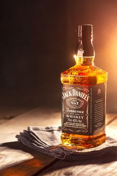 a bottle of jack daniels whiskey sitting on top of a wooden table next to a cloth