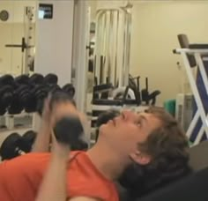 a man laying down in a gym with dumbs