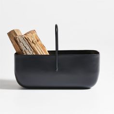 a black bowl with wood in it on a white background, there is also a fork and knife holder