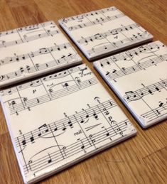 four coasters with sheet music on them sitting on a wooden table, one is white and the other is black