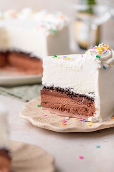 a slice of cake with white frosting and sprinkles on a plate