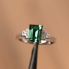 It is a lab green sapphire ring. The main stone is 6 mm*8 mm emerald cut.weight about 1.70 carats.The basic metal is sterling silver and plated with rhodium/14k white  gold/14k rose gold/14k yellow goldYou can also go to my shop Home for more elegant rings: https://www.etsy.com/shop/godjewelry?ref=hdr_shop_menu Customization is always welcome and please feel free to contact with me if you have any design ideas! Silver Platinum Emerald Ring With Gemstone, Silver Platinum Emerald Gemstone Ring, Green Emerald Ring With Brilliant Cut In Sterling Silver, Formal Green Sapphire Sterling Silver Ring, Green Sapphire Ring Sterling Silver, May Birthstone, Emerald Cut Sapphire Ring, Green Engagement Rings, Elegant Rings, Black Spinel Ring