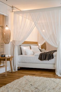 a white bed with sheer curtains and pillows