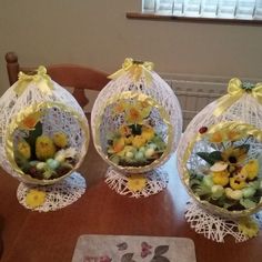 three baskets filled with flowers sitting on top of a wooden table