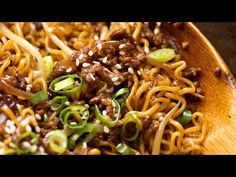 a wooden bowl filled with noodles, meat and veggies on top of it