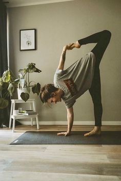 a woman is doing yoga on the floor in front of a potted plant with her hands behind her head