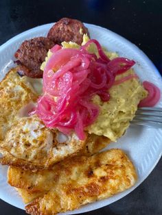 a white plate topped with meat and veggies on top of a table next to a fork