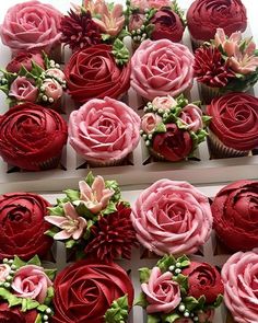 cupcakes decorated with pink and red flowers in a box