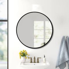 a white sink sitting under a round mirror