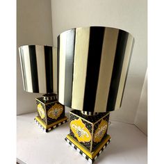 two black and white striped lamps sitting on top of a table next to each other