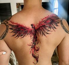 the back of a man's chest with red and black tattoos on it