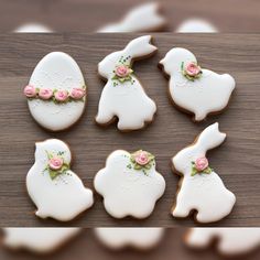 some decorated cookies are sitting on a wooden table with white frosting and pink flowers