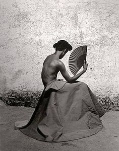 a woman sitting on the ground holding a fan