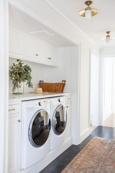 a washer and dryer in a white laundry room with an area rug on the floor