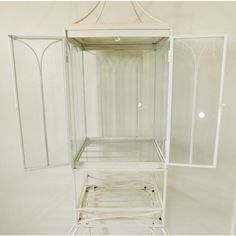 an empty white shelf with glass doors on the top and bottom shelves in front of it