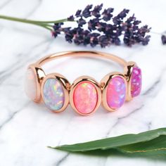 three opalite rings on top of a marble table next to purple flowers and leaves