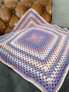 a crocheted blanket sitting on top of a couch next to a brown leather chair