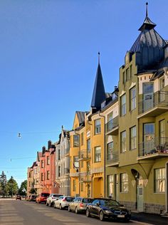 cars are parked on the street in front of tall buildings with steeple tops and balconies