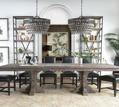 a dining room table with chairs and chandelier in the background, surrounded by framed pictures