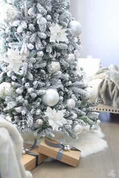 a white christmas tree decorated with silver ornaments