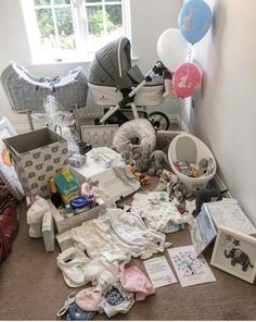 a room filled with lots of baby items and balloons on the floor next to a window