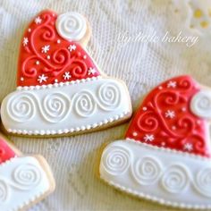 three decorated heart shaped cookies sitting on top of a white table cloth with swirly icing