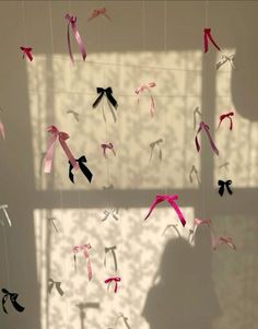 some pink and black ribbons are hanging from the ceiling in front of a white wall