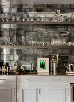 a kitchen with lots of glassware on top of the counter and cabinets below it