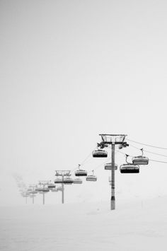 a ski lift is in the middle of a snow covered field with power lines above it