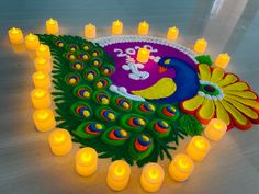 there is a decorated peacock with candles on the floor and in front of it are many lit candles