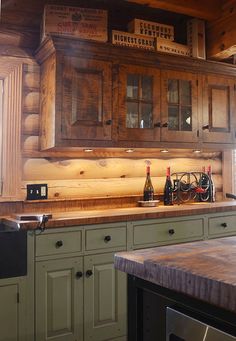 an old fashioned kitchen with wooden cabinets and counter tops, along with wine bottles on the bar