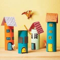 several paper houses are lined up on a table next to a bird flying over them