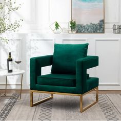 a green velvet chair with gold legs in a white living room, next to a table and potted plant