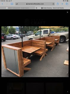 several wooden benches sitting in the middle of a parking lot with an umbrella over them