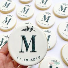 a hand holding a cookie with the letter m on it in front of many cookies