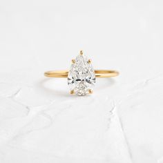 a pear shaped diamond ring on a white surface