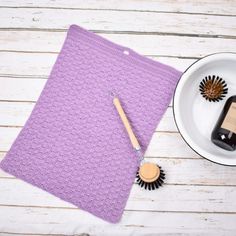 a purple crocheted placemat next to a bottle of wine and a brush