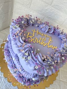 a birthday cake with purple frosting and flowers on it's side is shown